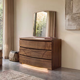 Comò contemporaneo Modigliani Piombini in vero legno di noce con specchiera coordinata e illuminazione LED integrata. Le forme sagomate, il disegno esclusivo dei frontali, le venature autentiche del legno e la luce soffusa esprimono l'equilibrio tra design italiano, innovazione e lavorazione artigianale.