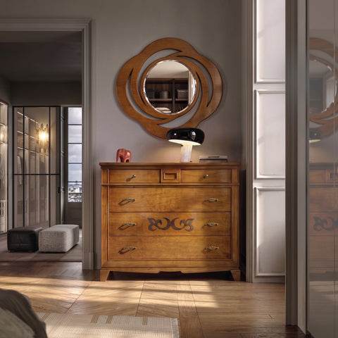 Luxuriöses Schlafzimmer mit Öffnung zum begehbaren Kleiderschrank, warm von rechts beleuchtet. Auf Fischgrätparkett steht das Como Classico Fünf-Schubladen-Kommode mit Geheimfach von Piombini in Kirschholz; darauf Snoopy-Lampe von Flos, roter Hermes-Elefanten-Fermacarte und ovale D'Este-Spiegelkonsole.