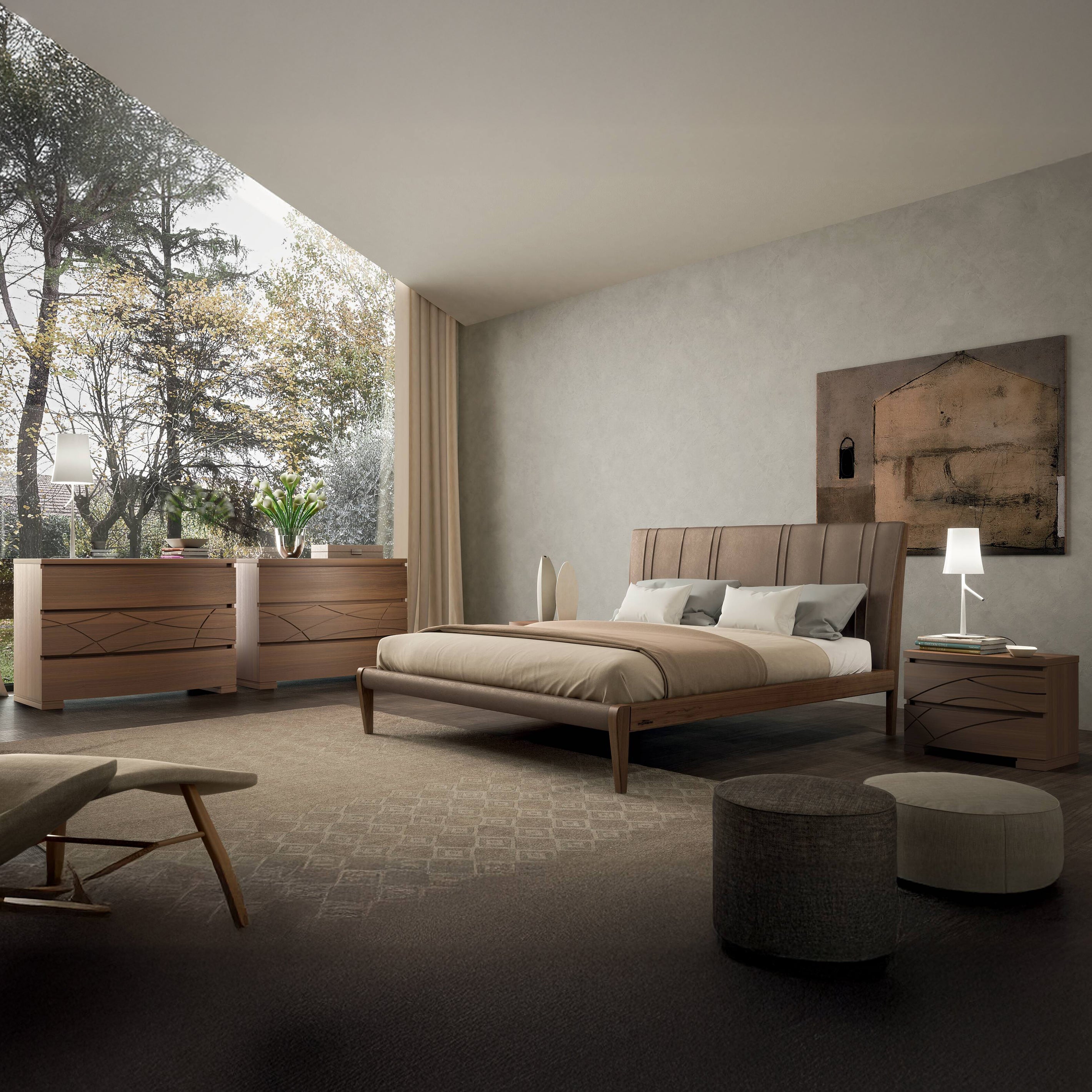 Camera matrimoniale con letto, comodino e comò in legno di noce della collezione Modigliani, ambientata in uno spazio moderno con ampia finestra panoramica.