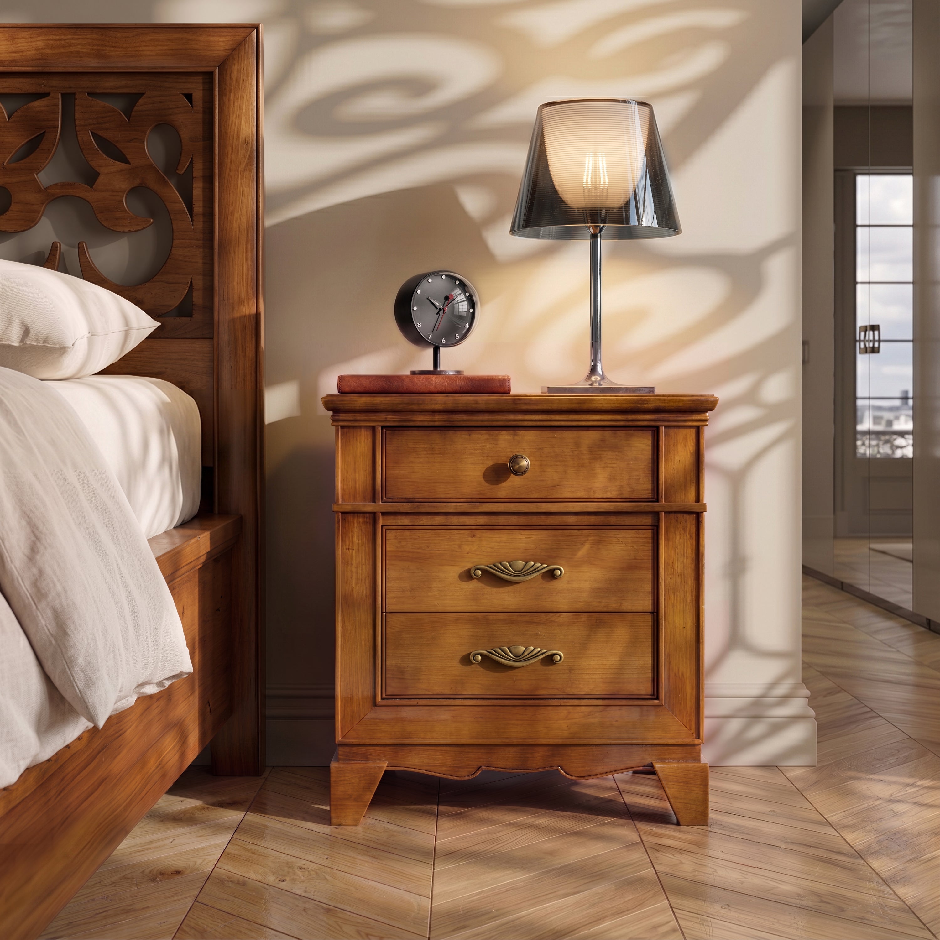 Front view of the classic Arte D'Este Piombini cherrywood bedside table with a Flos KTribe lamp and alarm clock on top. Chevron parquet floor and decorative shadows on the wall.
