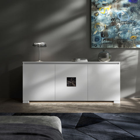 Credenza Modigliani Piombini a 3 ante in finitura Bianco Laccato con inserto in marmo nero Port Saint Lauren; ambientazione in stile Soft Modern con lampada Flos Bon Jour, vaso Venini Monofiore Balloton fumè, tappeto geometrico blu e divano moderno grigio.