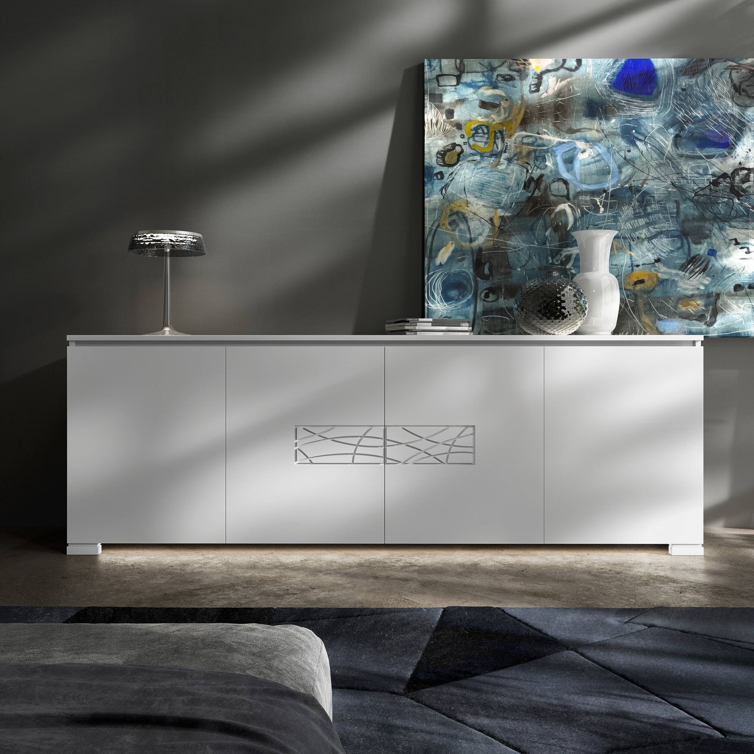 Credenza Modigliani Piombini a 4 ante in finitura Bianco Laccato con decoro Comete; ambientazione in stile Soft Modern con lampada Flos Bon Jour, vaso Venini Monofiore Balloton fumè, vaso Venini Opalino, tappeto geometrico blu e divano moderno grigio.