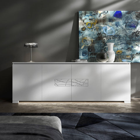 Credenza Modigliani Piombini a 4 ante in finitura Bianco Laccato con decoro Comete; ambientazione in stile Soft Modern con lampada Flos Bon Jour, vaso Venini Monofiore Balloton fumè, vaso Venini Opalino, tappeto geometrico blu e divano moderno grigio.