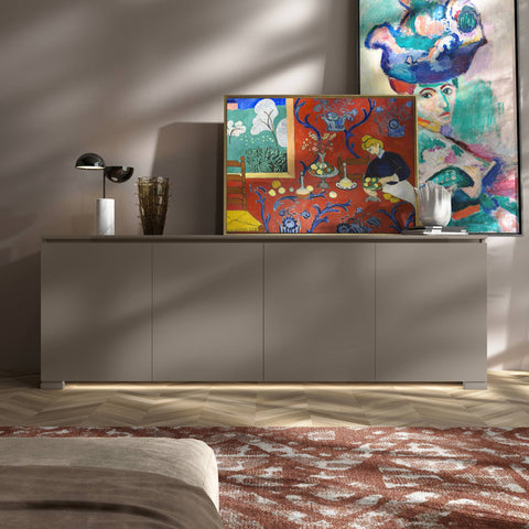 Credenza Modigliani Piombini a 4 ante in finitura Tortora Laccato con ante liscie; ambientazione in stile Soft Luxury con lampada Penta Elisabeth, vaso Venini Fazzoletto, vaso Venini Ritaglio, tappeto moderno rosso e divano moderno sabbia.