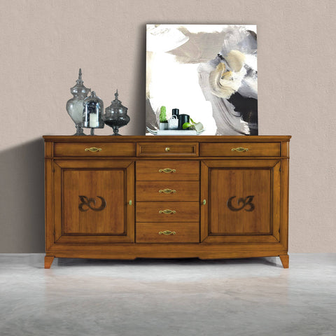 Credenza modello P3010 della collezione Arte d'Este di Piombini, in legno finitura GRN14 Bassano chiaro anticato. Design classico italiano con due ante laterali, due cassetti sopra le ante e cinque cassetti centrali, esposta contro una parete neutra con decoro contemporaneo e vasi in vetro.