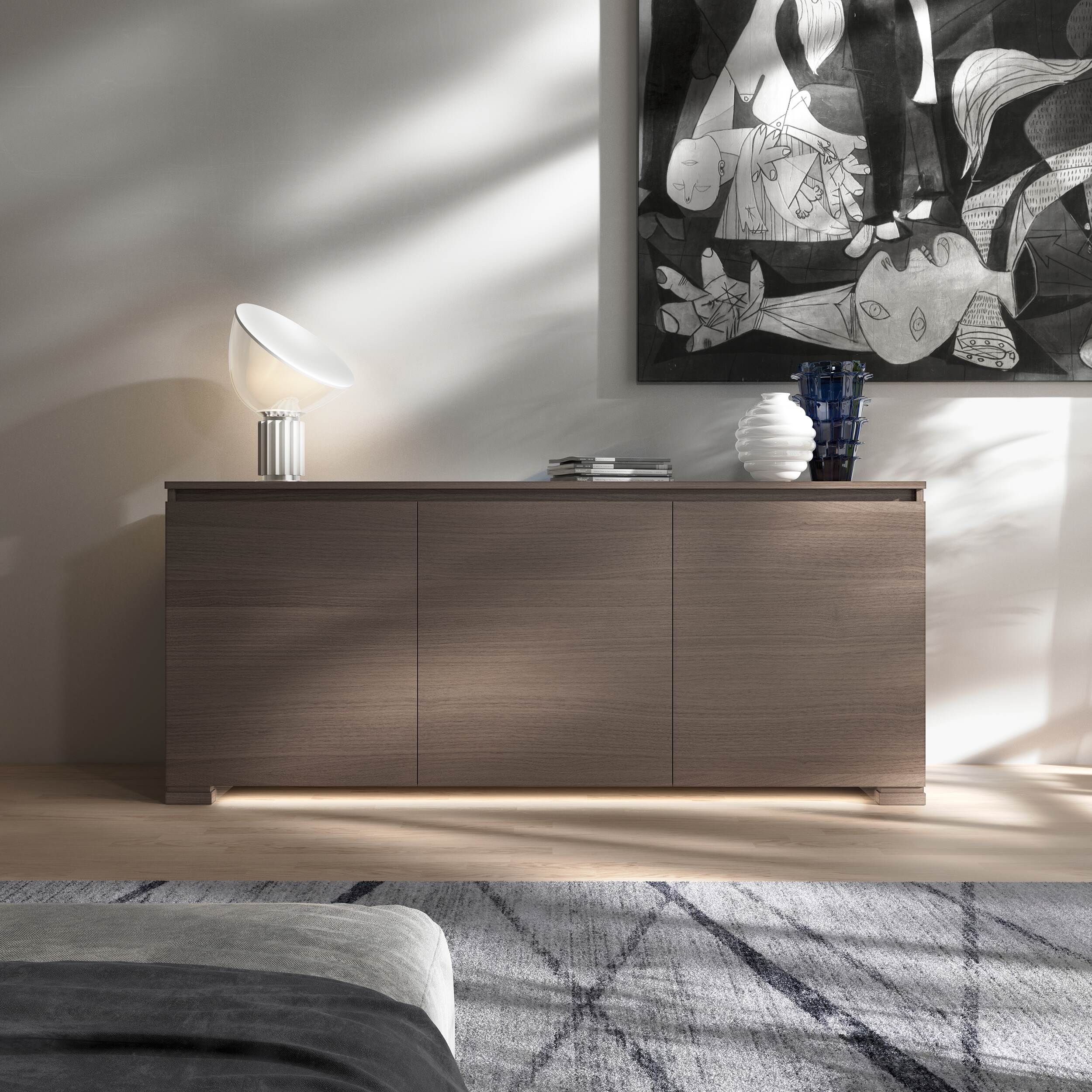 Credenza Modigliani Piombini a 3 ante in finitura Cenere con ante lisce; ambientazione in stile Minimalismo Nordico con lampada Flos Taccia, vaso Venini Deco bianco e vaso Venini Ritaglio blu, tappeto geometrico e divano moderno grigio.
