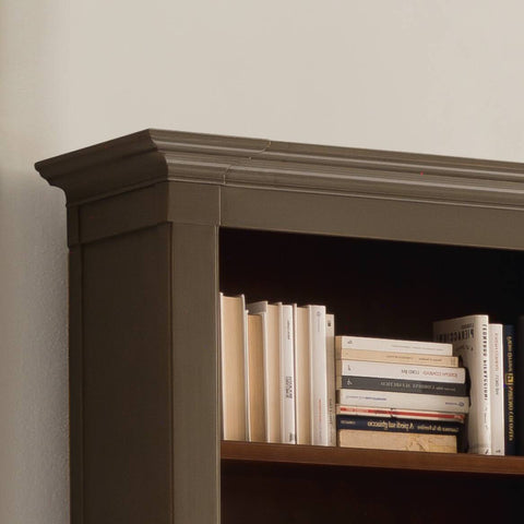 Particolare della libreria classica Codice 8813G, con cornici importanti e lavorazione artigianale. La finitura laccata patinata anticata colore tortora 28 mostra l’effetto consumato tipico della tradizione Piombini, mentre l’interno in contrasto con finitura legno esalta la profondità e la raffinatezza del mobile. Un esempio di eleganza e maestria italiana.