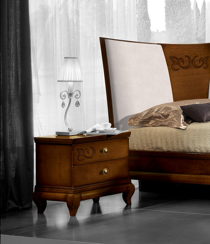 Letto matrimoniale classico con box contenitore Piombini D'Angiò, codice P4101/CN/160, ambientato con comodino coordinato codice P4100 SX/DX. Testata rivestita in vera pelle con decoro centrale applicato in Noce Canaletto.