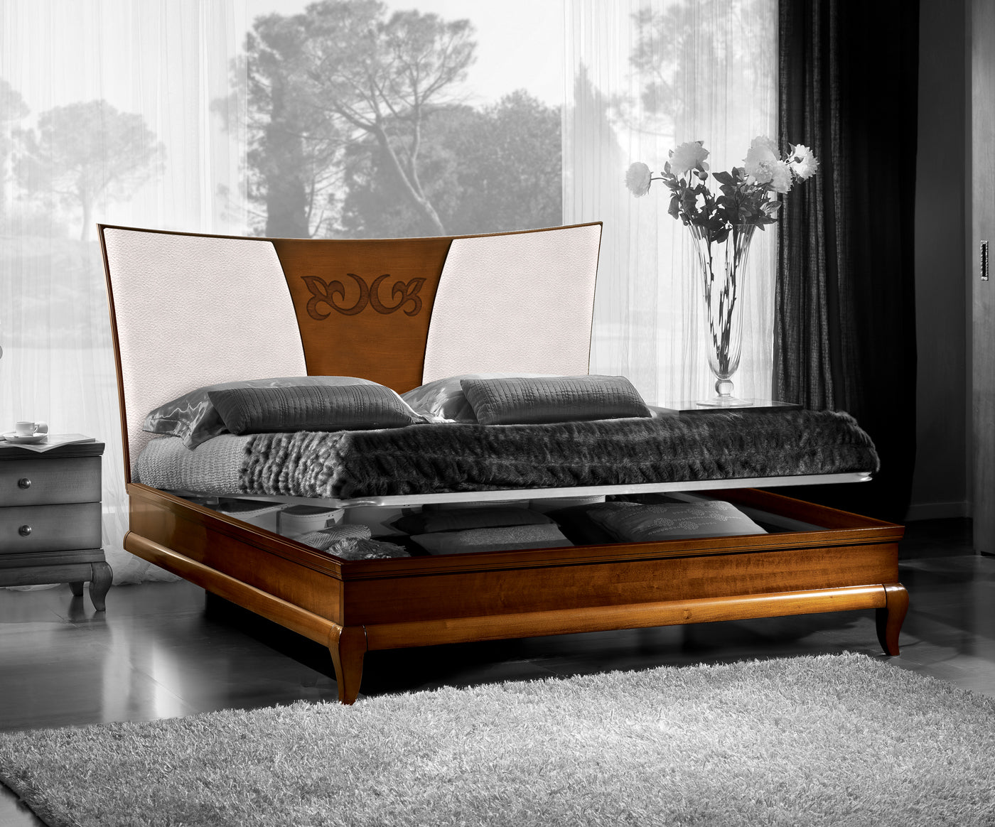 Letto matrimoniale classico con box contenitore Piombini D'Angiò, codice P4101/CN/160, struttura in legno, testata rivestita in vera pelle con decoro centrale applicato in Noce Canaletto.