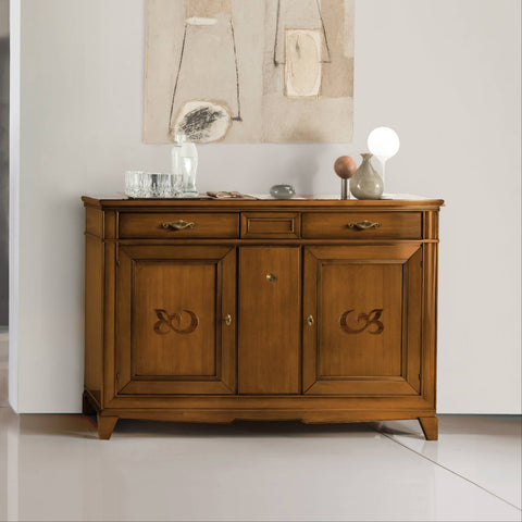 Credenza classica D'Este P3009 in legno, con due porte decorate e tre cassetti, ambientata in un soggiorno elegante dai toni chiari.
