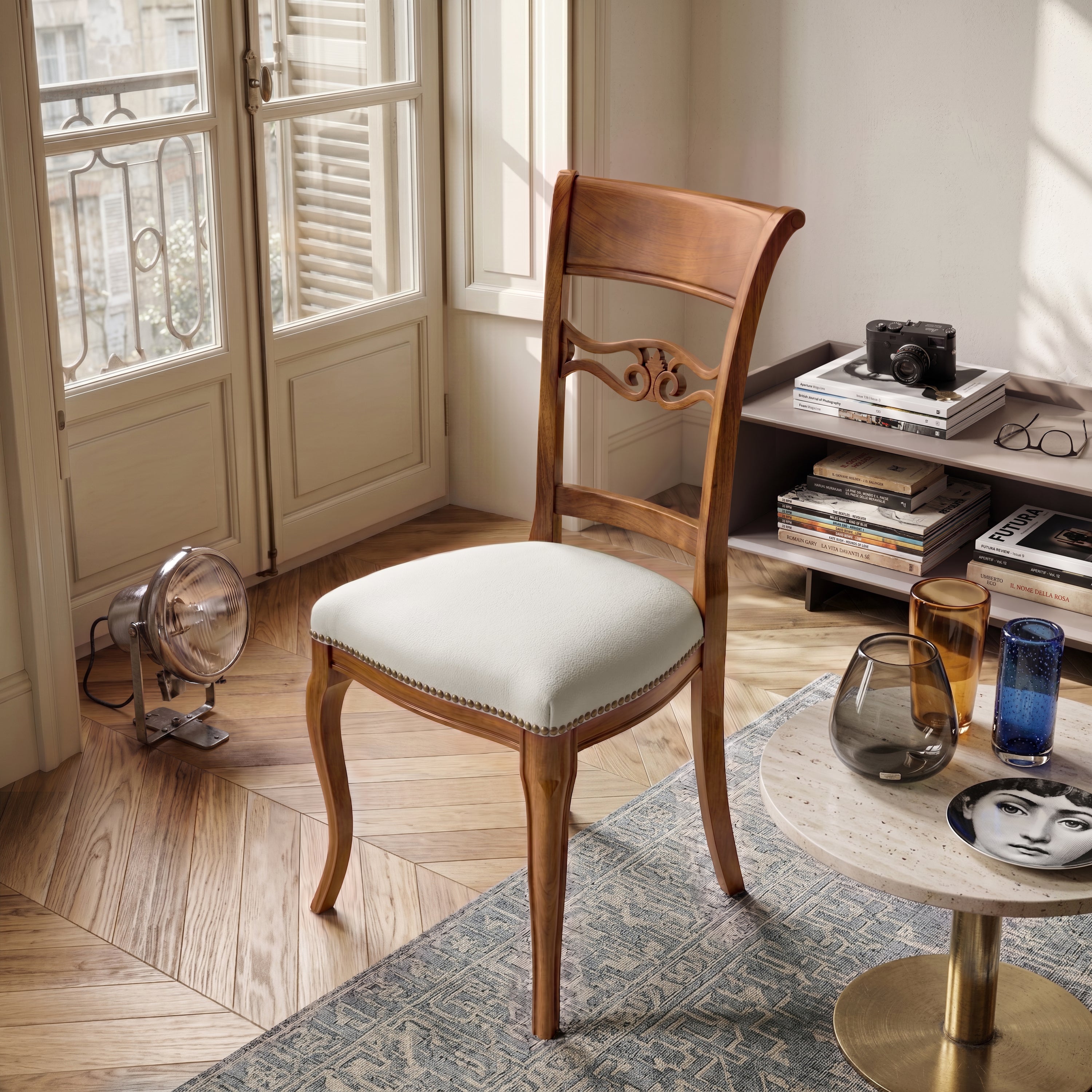 Sedia classica Vittoria in legno massello con seduta imbottita rivestita in vera pelle Siviglia Top Bianco, ambientata in un soggiorno elegante con pavimento in legno, tavolino moderno e luce naturale