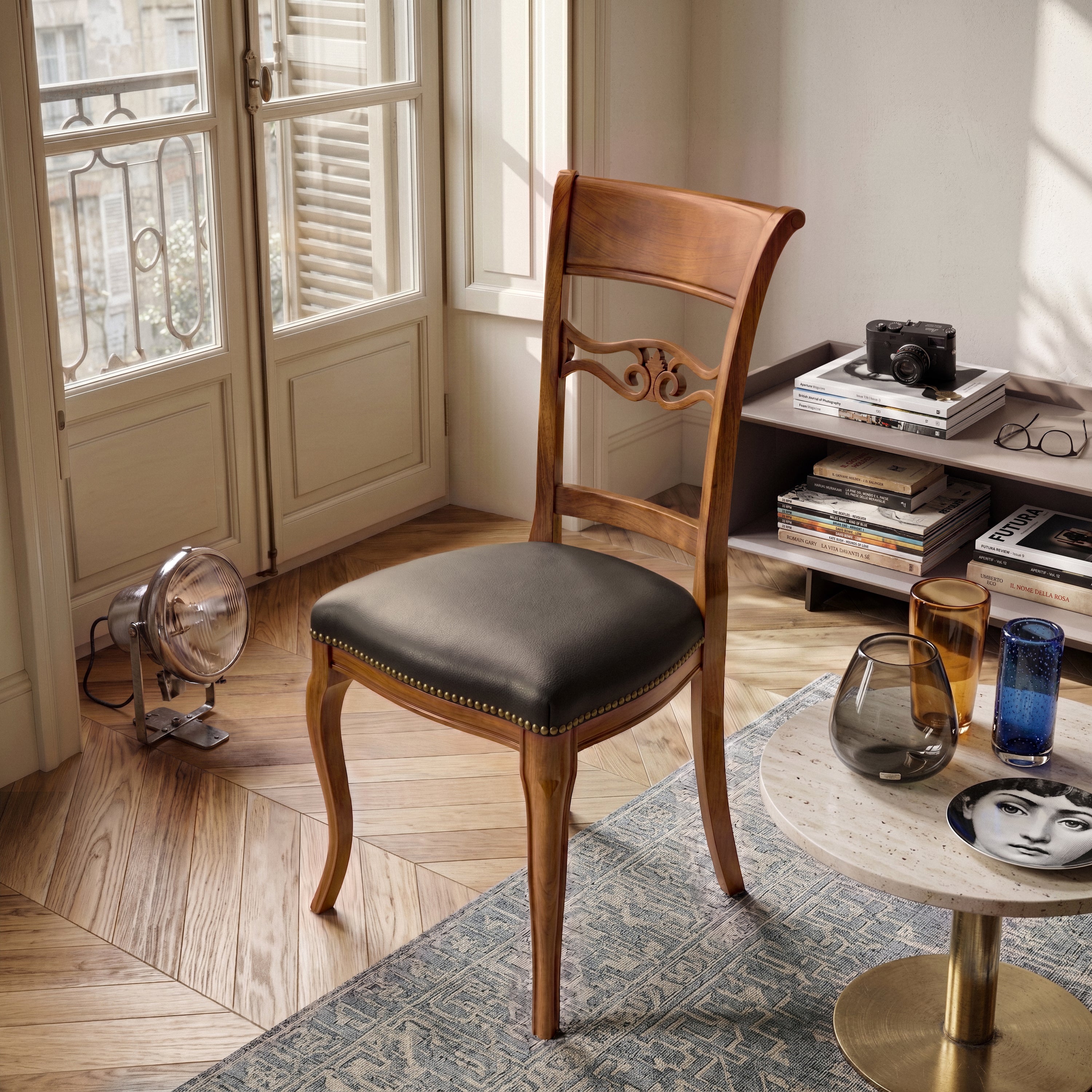 Sedia classica Vittoria in legno massello con seduta imbottita rivestita in vera pelle Siviglia Top Testa di Moro, inserita in un ambiente elegante con pavimento in legno e arredi contemporanei