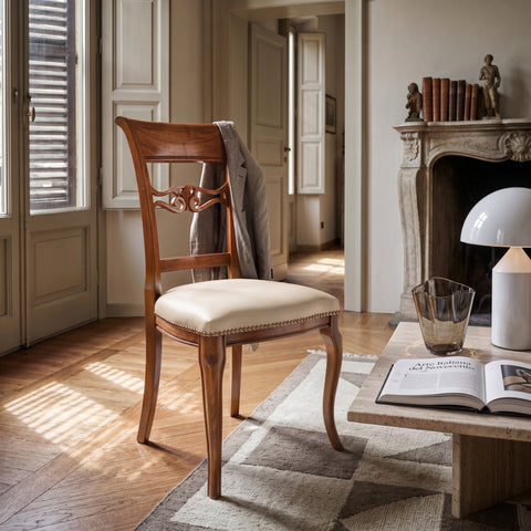 Sedia classica Vittoria in legno massello con seduta imbottita rivestita in vera pelle Siviglia Top Ecrù, inserita in un ambiente elegante e luminoso con pavimento in legno e tavolino moderno