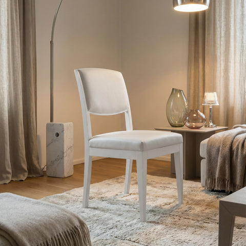 Sedia da pranzo moderna con struttura in legno di noce canaletto Laccato Bianco e rivestimento in pelle Bianca , ambientata in un salotto elegante e luminoso.