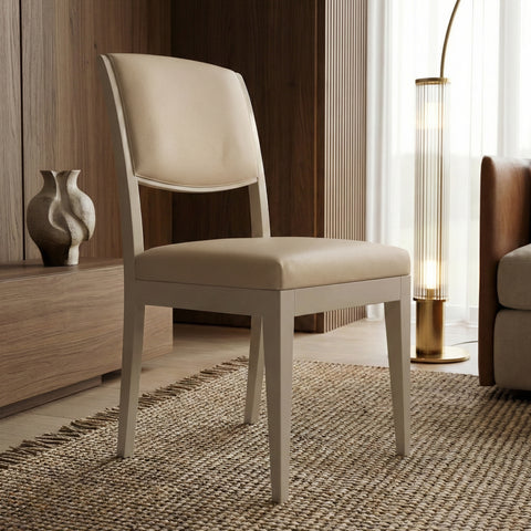 Sedia da pranzo moderna con struttura in legno di noce canaletto Laccato Onice e rivestimento in pelle Crema, ambientata in un salotto elegante e luminoso.