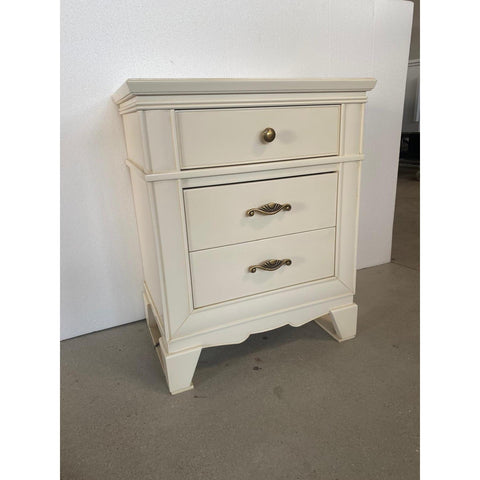 Vista frontale del comodino Arte D’Este codice P3100/L/26, con tre cassetti perfettamente rifiniti. La finitura 26 Burro Consumato patinato Anticato conferisce profondità e delicatezza alla superficie. Il primo cassetto è impreziosito da un pomolo rotondo, mentre i due inferiori sfoggiano maniglie in metallo lavorato con decoro centrale. L’immagine valorizza le proporzioni armoniche, la cornice sagomata e l’eleganza artigianale del mobile Piombini.