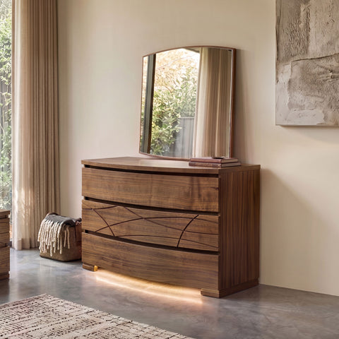 Frontansicht einer modernen, geformten Kommode aus Walnussholz mit unterer LED-Beleuchtung, SKU 8270D, gekrönt vom passenden modernen, geformten Spiegel, SKU 8275, in einem hellen, eleganten Schlafzimmer.