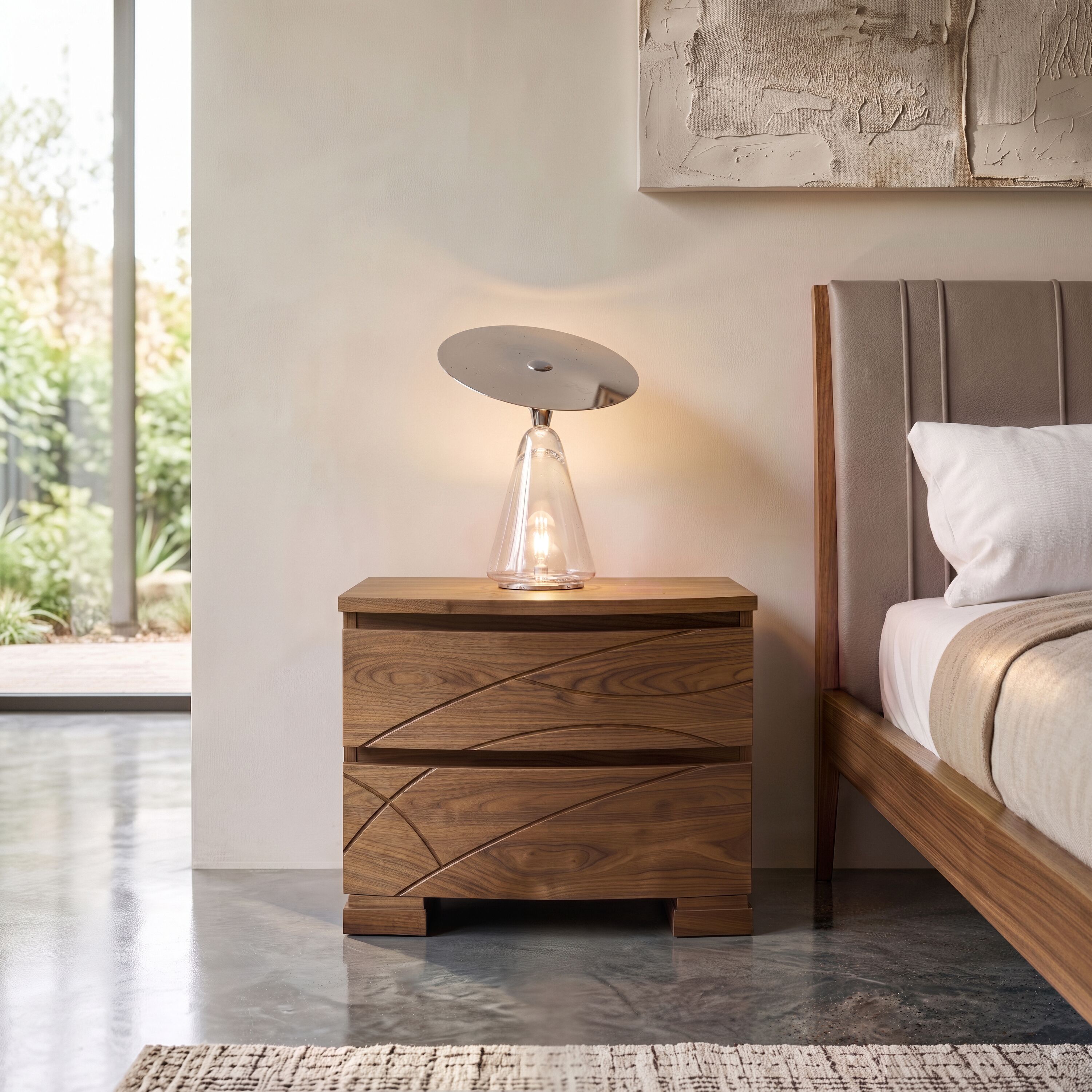 Comodino contemporaneo in vero legno di noce della collezione Modigliani Piombini. Le incisioni decorative Comete, le venature naturali del legno e l'ambientazione accanto al letto raccontano il design italiano e l'eleganza di una camera da letto artigianale.