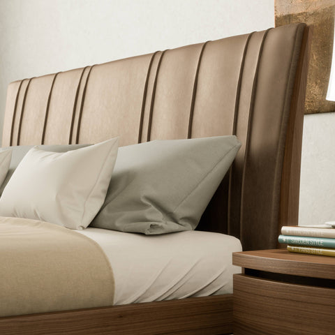 Detail of the upholstered headboard in taupe leather with vertical stitching on the wooden bed from the Modigliani collection. Elegant design and Italian craftsmanship to celebrate the 1925–2025 centenary.