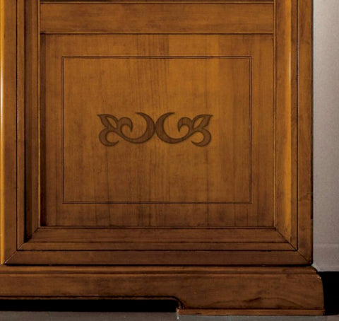 Dettaglio dell'anta scorrevole della libreria classica D'Este Piombini con pannello bugnato, intarsio decorativo in Noce Canaletto e solido basamento in legno massello. Un particolare che valorizza la qualità della lavorazione artigianale italiana e l'equilibrio delle proporzioni del mobile.