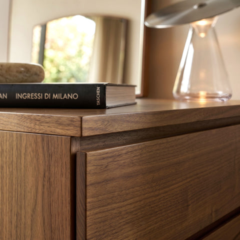 Dettaglio costruttivo e finitura artigianale dell'angolo superiore del comò in noce, codice SKU 8270D, che mostra la venatura del legno, la maniglia a gola integrata per l'apertura del cassetto e libri decorativi sul top.