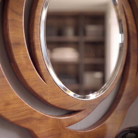 Dettagled close-up of the Ovale Traforata D'Este Classic Mirror by Piombini, focusing on the cherry-finish wood frame, curved carvings, and beveled mirror edge.