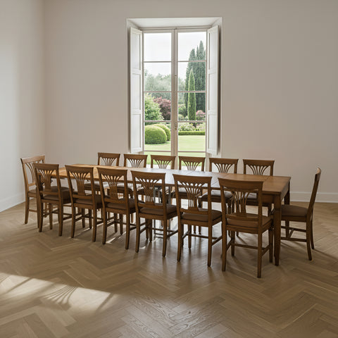 Grande tavolo allungabile in legno Tiziano di Piombini, visto in prospettiva e preparato per accogliere 14 persone in una sala da pranzo luminosa, con parquet a spina di pesce e alta finestra aperta sul giardino – RH970