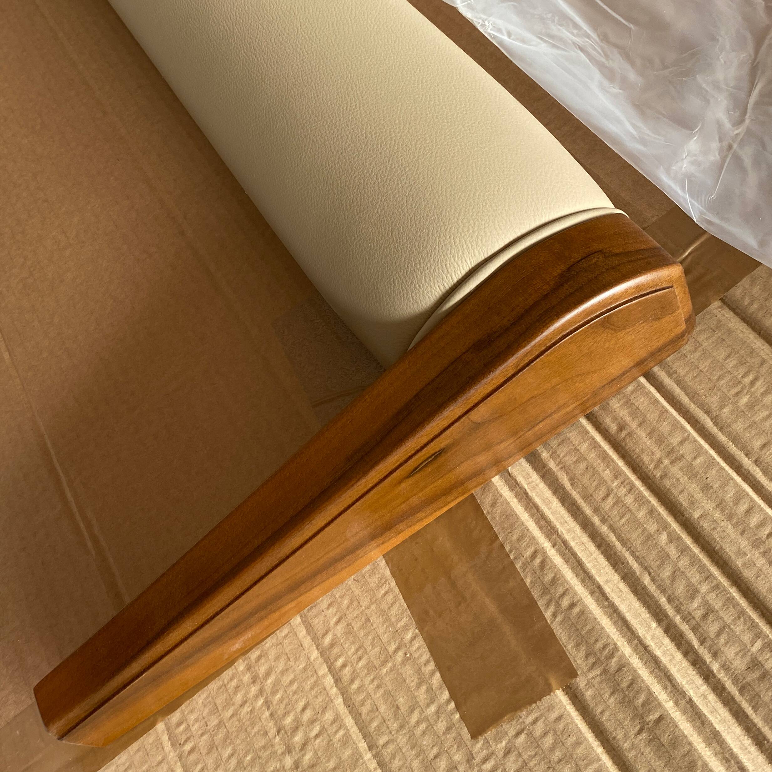 Dettaglio della struttura in legno di noce del letto Modigliani con rivestimento in pelle beige sulla pediera. Lavorazione artigianale evidenziata dalla luce naturale. 